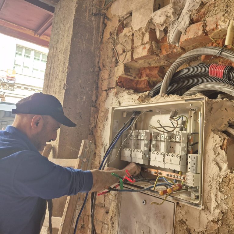 Elektriker bei der Altbausanierung eines Sicherungskastens und neuer Elektroinstallation